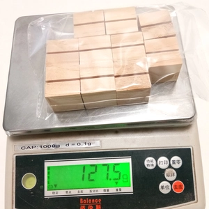 Macro shot of 10-piece wooden postcard bases on a scale showing weight of 127.5g