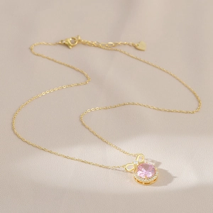 Detailansicht einer Goldkette mit rosa Zirkon-Anhänger und einer Kristal-Schleife