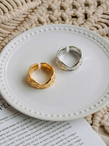Detailed top view of gold and silver chunky irregular wavy textured rings on a ceramic plate