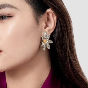 Elegant 18K gold and silver petal flower stud earrings worn by a model in a close-up
