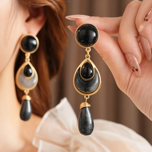 Close-up of vintage flower teardrop earrings with black stones in a golden setting