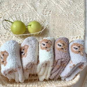 Close-up of five pairs of thick coral fleece socks with cute bear patterns in a basket