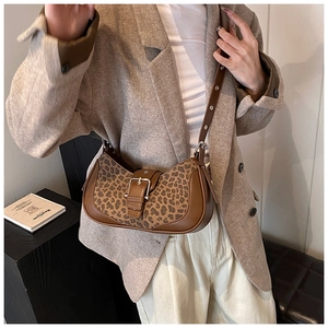 Sac bandoulière chic à motif léopard porté par un mannequin dans un cadre intérieur chaleureux