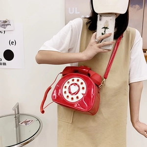 Detail of red patent leather crossbody bag in retro telephone shape with dial design
