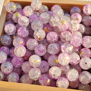 Close-up of lilac and white glass beads with gold foil and marble texture in wooden box
