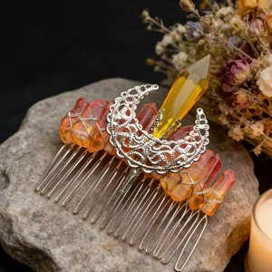 Macro shot of orange crystal hair comb with moon charm on natural stone background