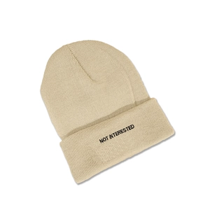 Detailed view of the NOT INTERESTED black embroidery on this beige ribbed knit beanie hat