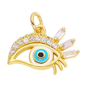 Macro detail of golden evil eye charm with blue enamel and sparkling white crystals