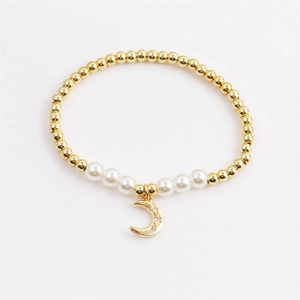 Gold beaded pearl bracelet with a sparkling zircon moon pendant on white background