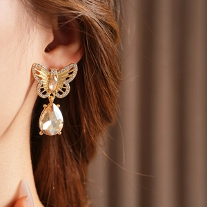 Gros plan détaillé de boucles d'oreilles papillon vintage dorées avec cristal goutte d'eau