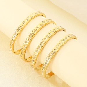 Detail of four 18K gold-plated titanium steel bangles with diverse engraved patterns