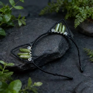 Detail of handmade cat ear headband with green crystals and beads on natural rocks