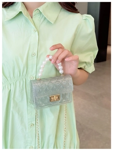 Close-up of glitter jelly bag with pearl handle and golden chain shoulder strap