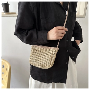 Detail of beige woven crossbody bag with slim faux leather straps and natural texture