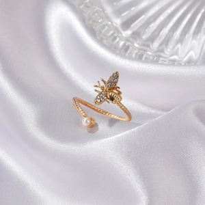 Close-up of golden bee ring with pavé rhinestones, small pearl, and twisted rope band