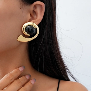 Close-up of vintage golden spiral earrings with a black oval gemstone on a model