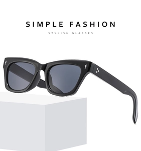 Detail of black square sunglasses with silver arrow accents and star rivets on white block