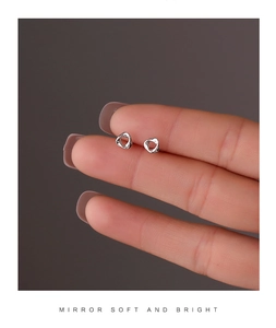 Macro detail of minimalist silver twisted stud earrings held to show scale and finish