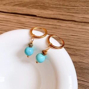 Détails de boucles d'oreilles bohèmes dorées avec perles turquoise sur bois