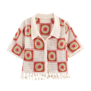 Detail of crochet hollow short sleeve cardigan with floral patterns and tassel hem