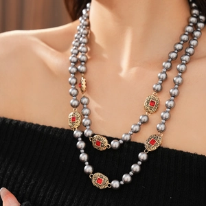 Details einer Vintage zweilagigen grauen Perlenkette mit Goldakzenten und roten Edelsteinen