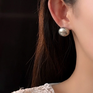 Close-up of elegant silver round stud earring worn on model for a minimalist fashion look
