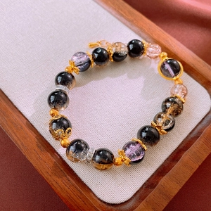 Detailed macro view of beaded bracelet with black crystals and gold-plated floral spacer beads