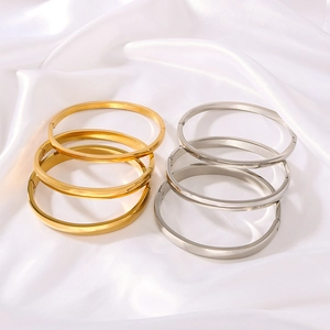 Minimalistische Edelstahlarmbänder in Gold und Silber auf eleganter weißer Seide
