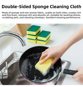 Dual-sided scrubbing sponge cleaning a black frying pan in a kitchen sink setting