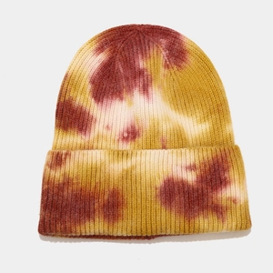 Detail of tie-dye knit beanie showing vibrant yellow, red, and white marbling effects