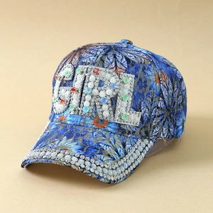 Detail of blue floral baseball cap featuring pearl and rhinestone GIRL letter emblem