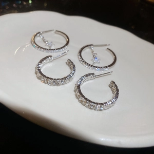 Macro detail of silver C-shaped star hoop earrings with sparkling cubic zirconia pavé