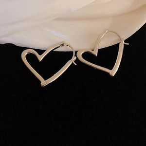 Detailed view of silver heart-shaped hoop earrings on elegant silk and velvet textures