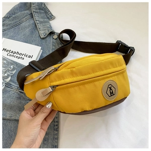 Detailed view of yellow canvas fanny pack with brown PU leather base and logo patch