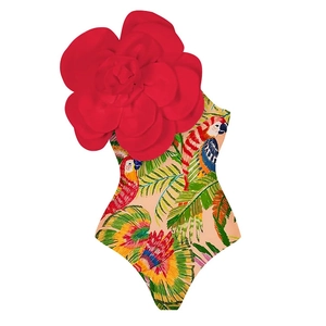 Detail of girls one-shoulder swimsuit featuring a large red 3D floral accent and parrot print