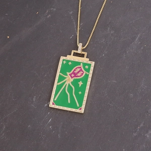 Detail of green enamel square pendant with purple creature design and gold stars