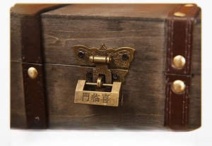 Detail of vintage wooden storage box featuring bronze butterfly lock and leather trim