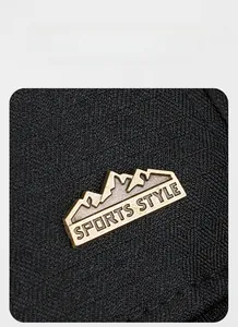 Detail of mountain-shaped metal badge with SPORTS STYLE text on black woven baseball cap