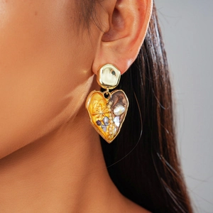 Detailed close-up of a vintage heart earring with gold plating and pearl shell inlay