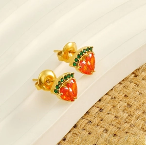 Vue macro de boucles d'oreilles gemmes orange en forme de cœur et cristaux verts