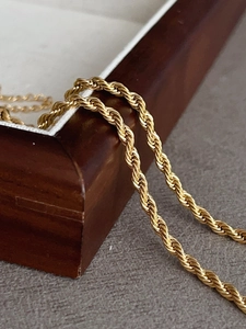 Detail of 18k gold plated stainless steel rope chain draped over a wooden jewelry box