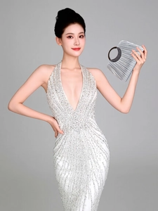Silver pleated evening clutch bag held by a model in a sequined white dress