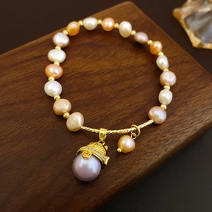 Macro detail of multi-color freshwater pearls and golden pendant on wooden stand