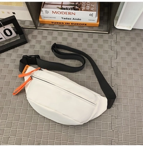 Close-up of white nylon chest bag featuring orange decorative zipper pulls and black buckle