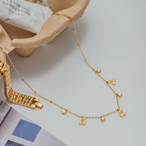 Dettaglio di una collana con ciondolo a ciliegia dorata con cristalli su catena a maglie