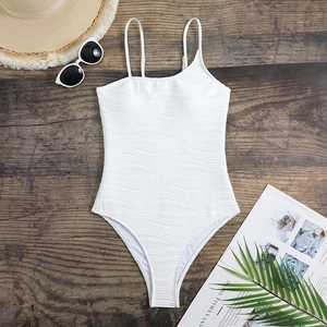 Close-up of white one-piece swimsuit with wavy texture and summer vacation accessories