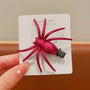 Detail of pink glitter spider hair clip on card showing sparkling texture and size
