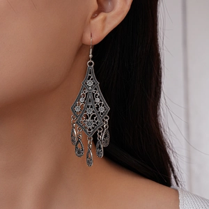 Detailed view of bohemian style antique silver drop earrings on a model with tassel fringe