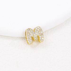 Detailed macro view of a gold-plated letter M pendant set with sparkling cubic zirconia