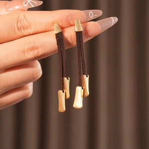 Detailed close-up of long brown suede rope tassel earrings with matte gold metal accents